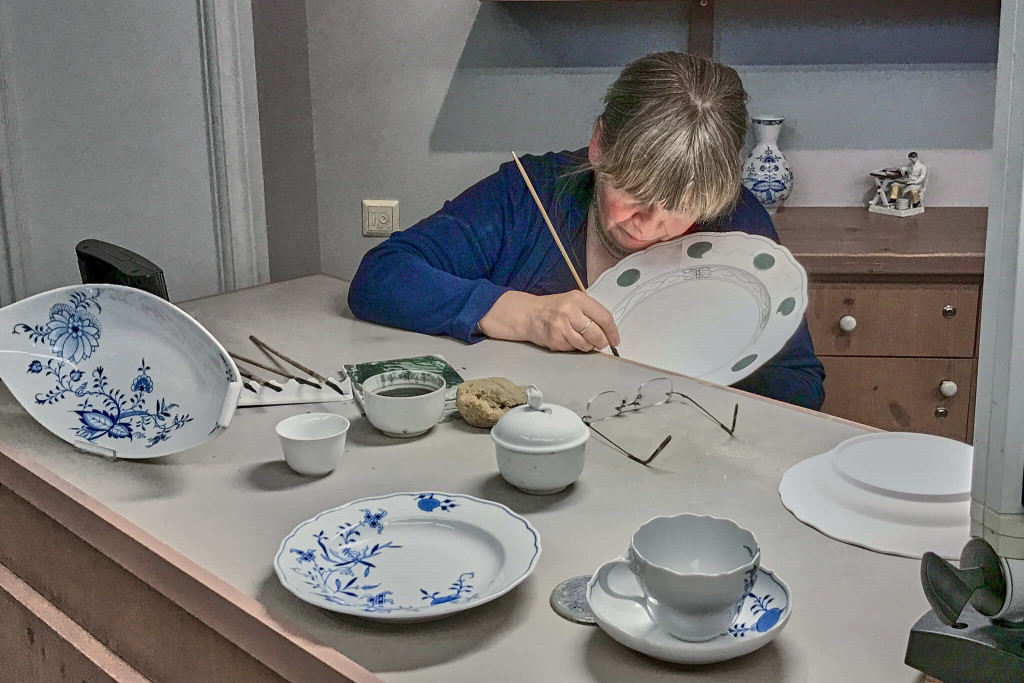 The painter applied the cobalt blue colour to a plate.