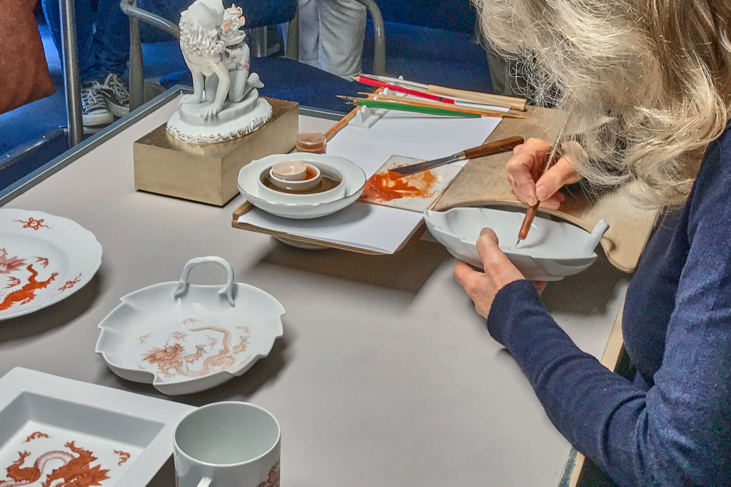 An artisan demonstrated the on-glaze painting. Colours were applied by hand to the glaze of the porcelain.